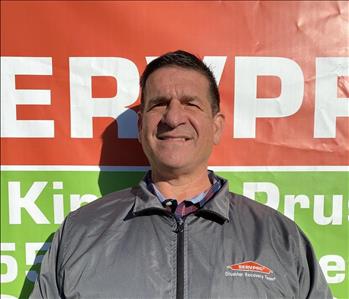 Male Employee Standing in front of SERVPRO Banner 