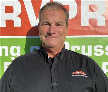 Male Employee Standing in front of SERVPRO Banner 